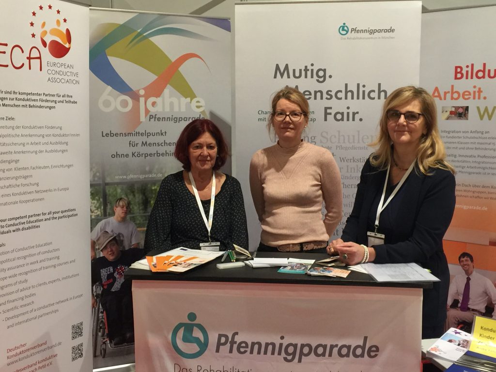 Information Stand with ECA roll-up showing three people of ECA at RehaKind congress in Munich