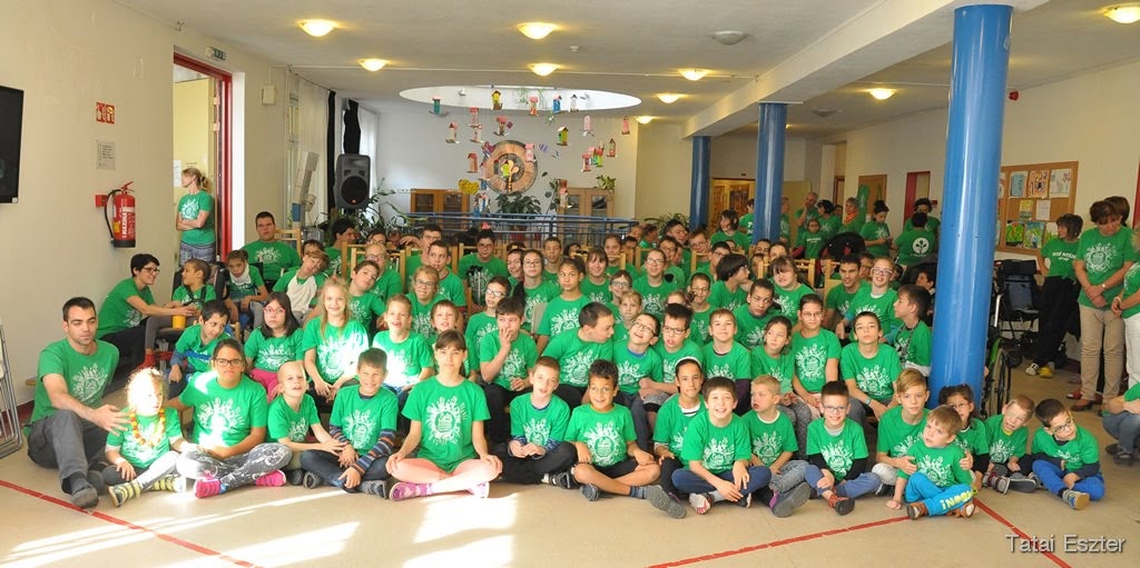 Picture of a group of ca. 30 children all with green t-shirt, sitting on floor of school in Hungary at WCPD.
