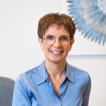 Esther Horvath Tothne, hellbraune short hair, glasses, light blue Bluse, smiling.
